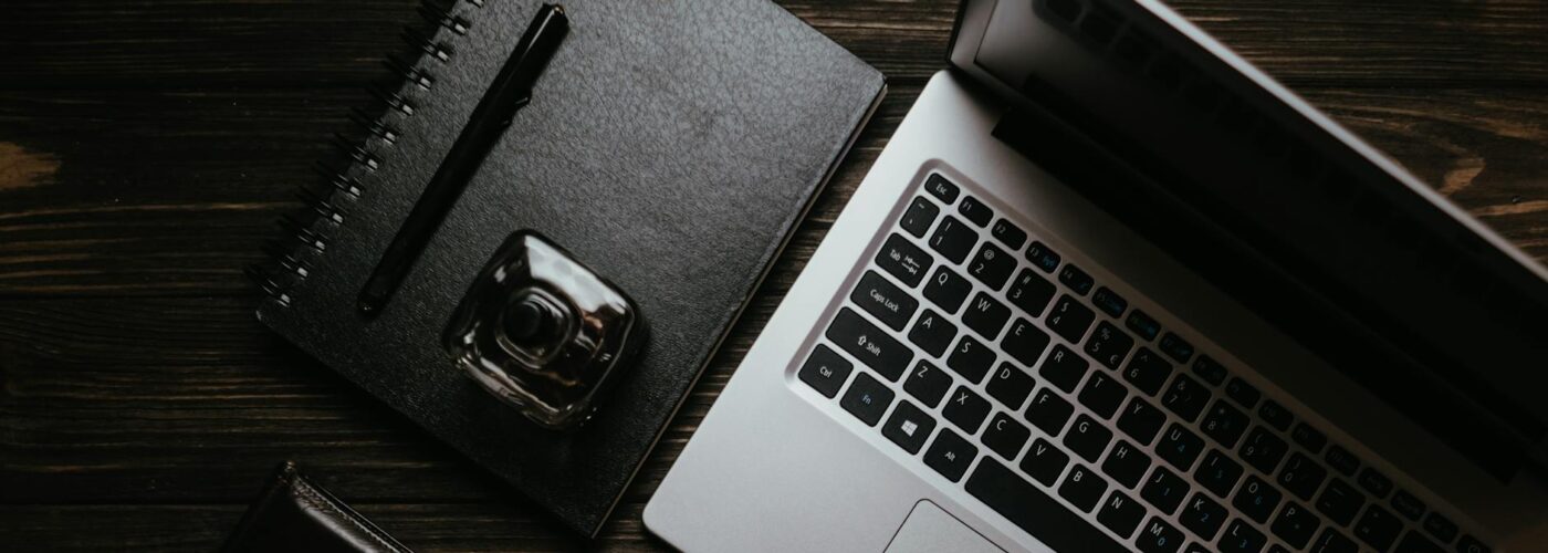 black notebook and wallet beside a laptop